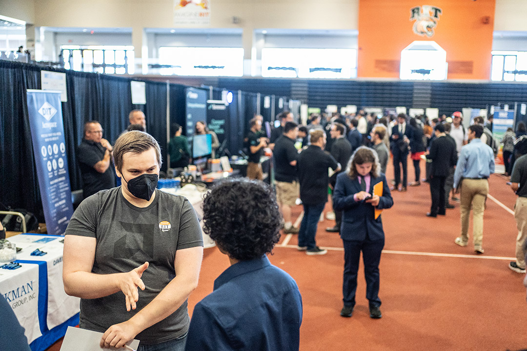 recruiter talking to a college student at a career fair.