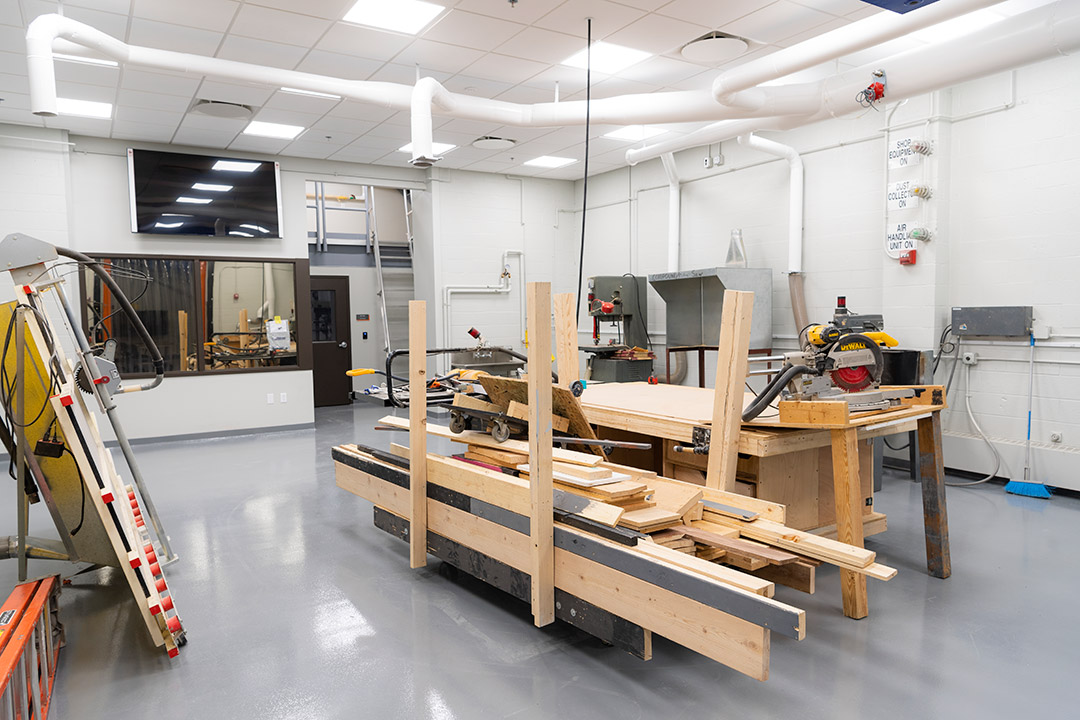 a room with woodworking machines and stacks of scrap wood.