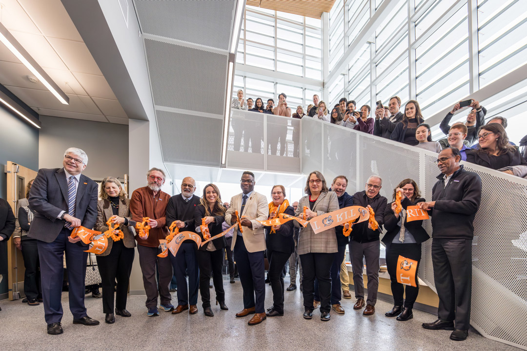 several adults stand in a modern building for a ribbon cutting