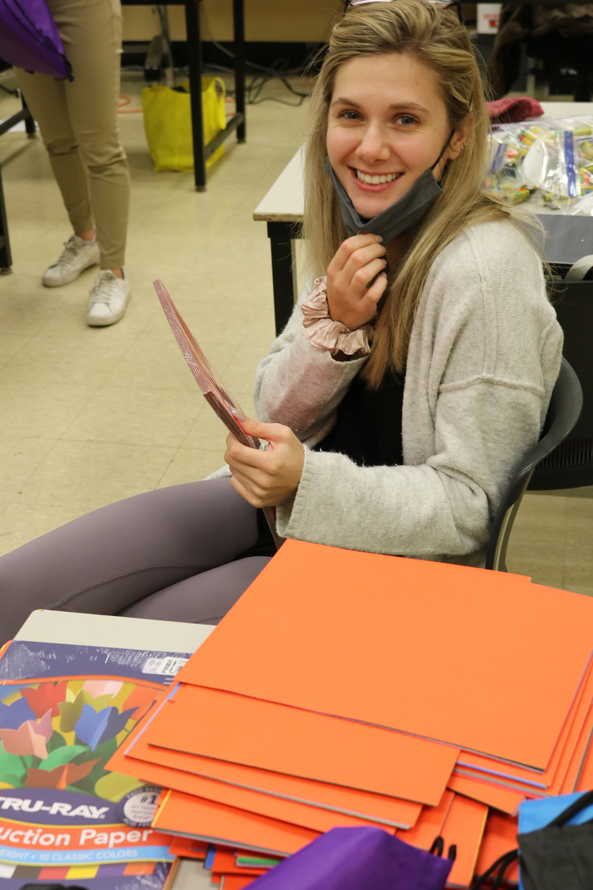 A student poses beside orange paper included in the art kits.