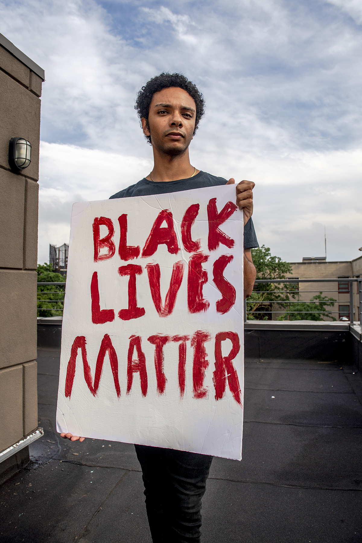 a boy holds a sign that reads Black Lives Matter in red.