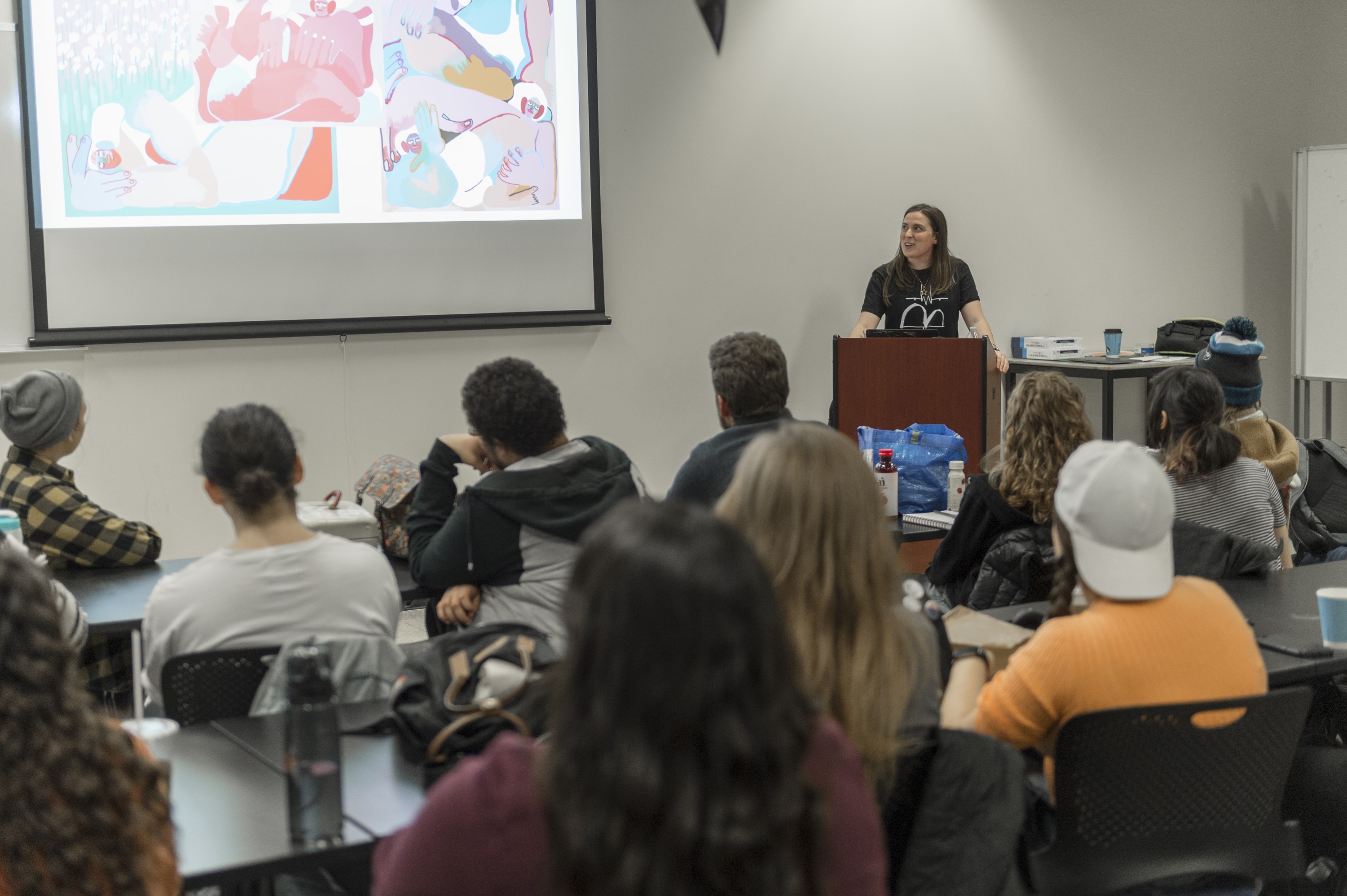 Amber Vittoria stands at a podium speaking to students