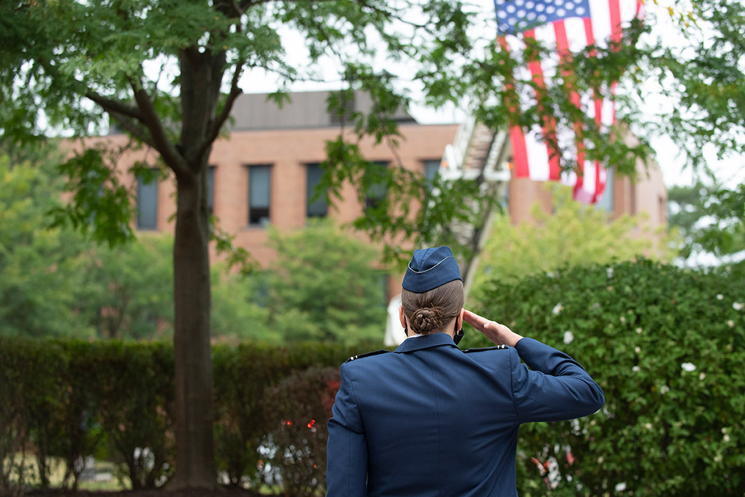 ROTC member saluting American flag.