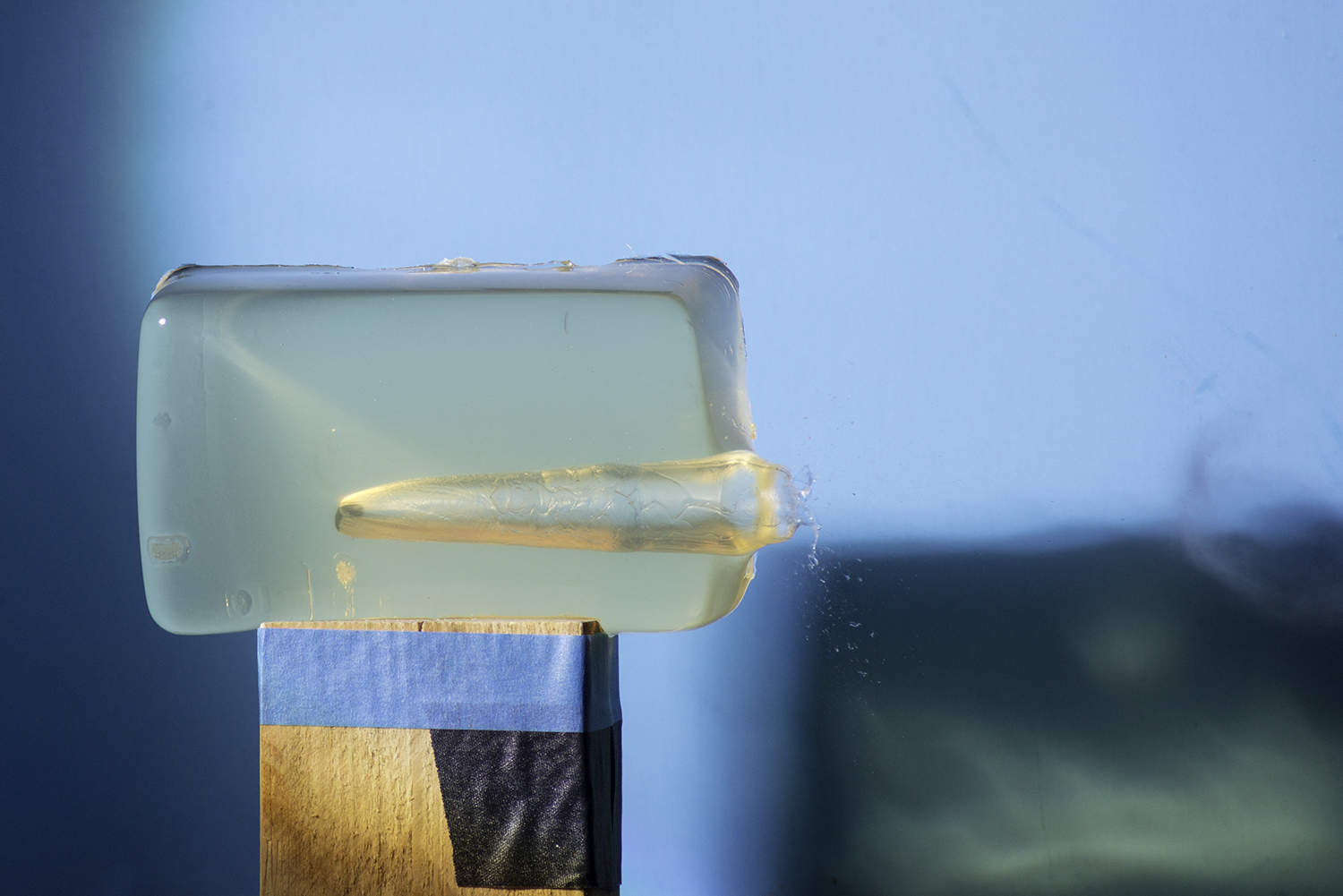 A photo of a bullet going through jello.