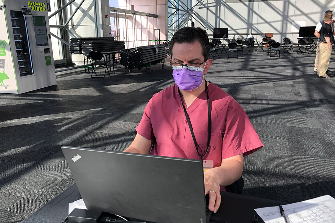 doctor wearing scrubs and working on a laptop.