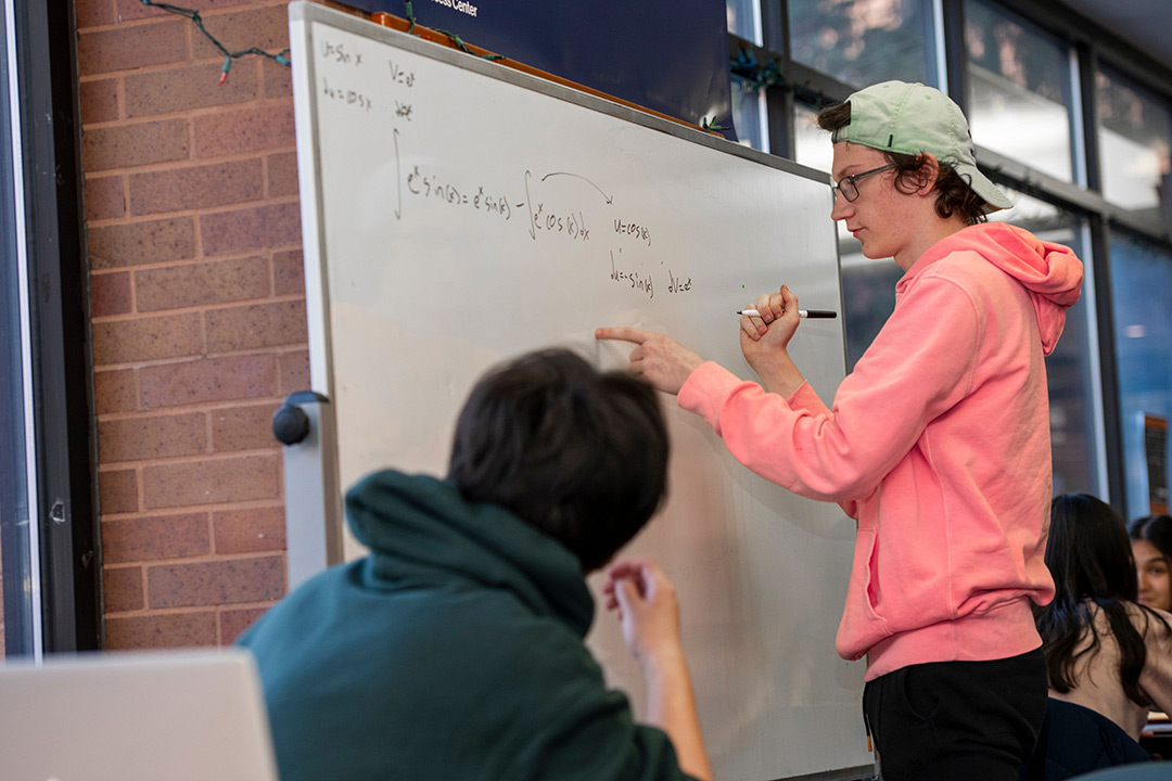 college student writing on a dry-erase board.