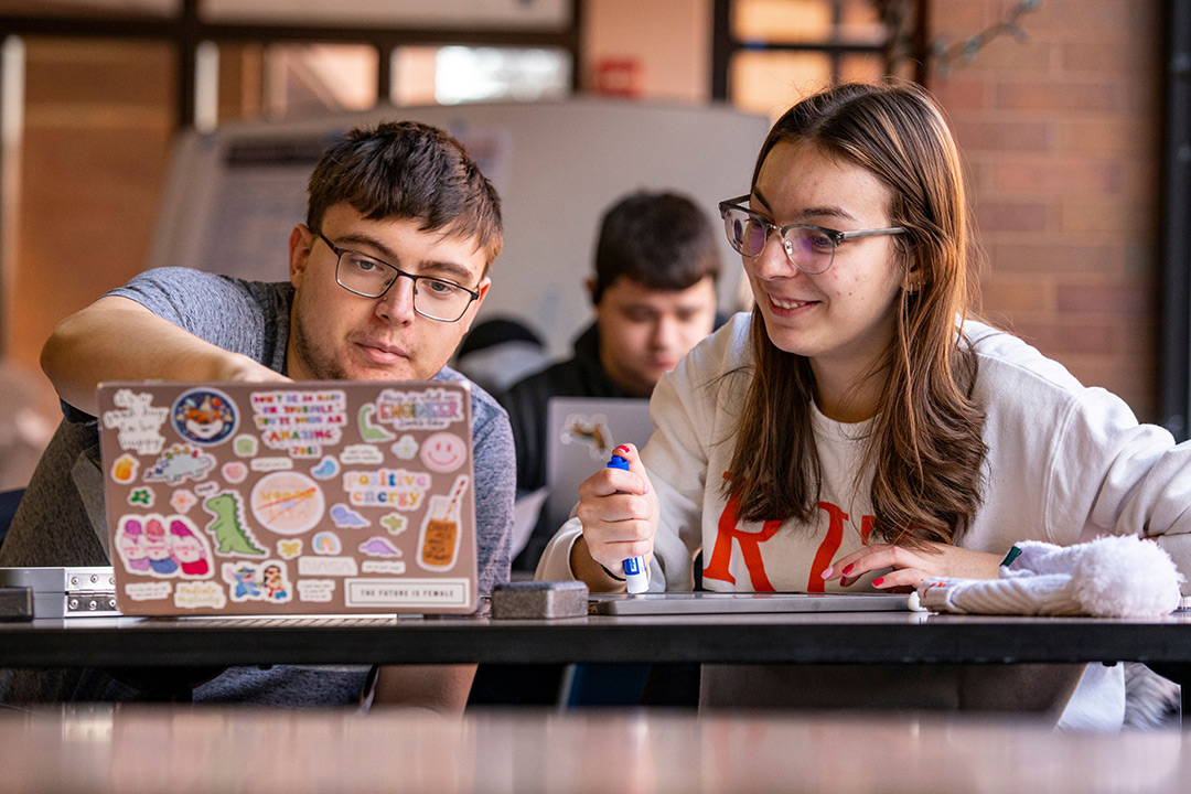 two college students looking at a laptop.