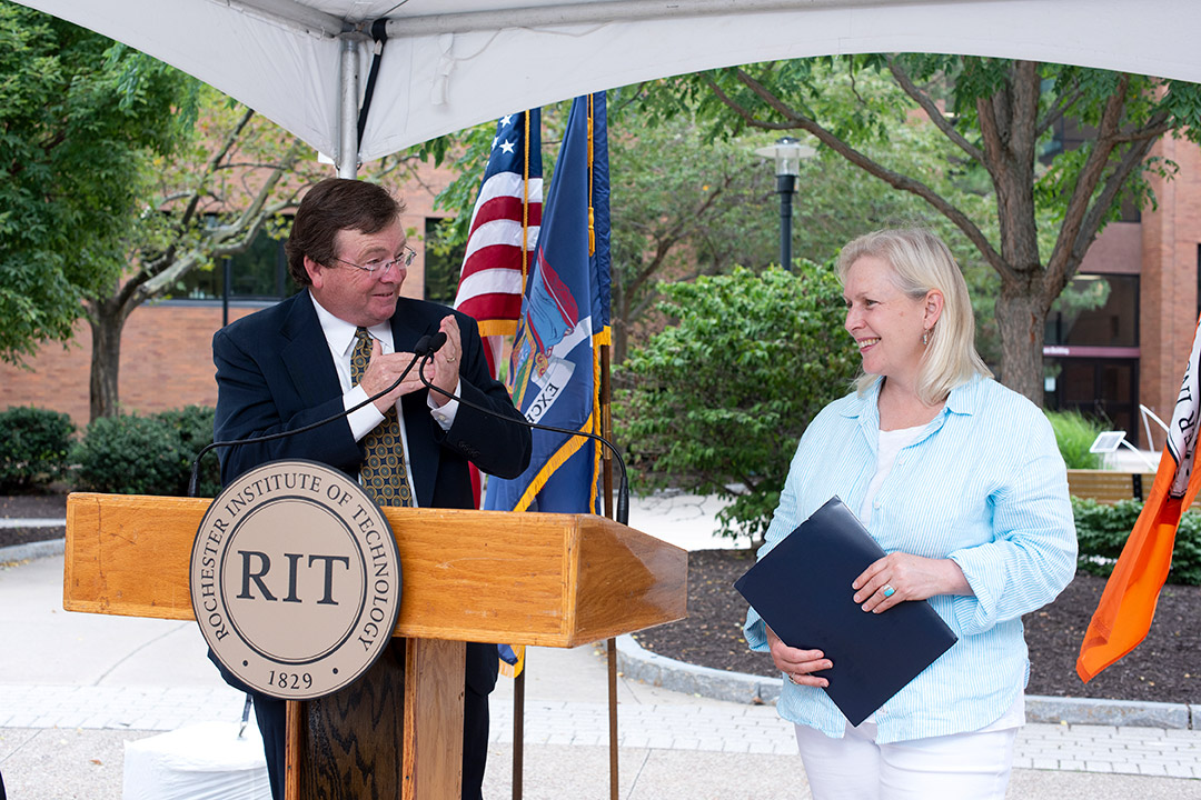 NTID president standing at a podium next to Senator Kirsten Gillibrand.
