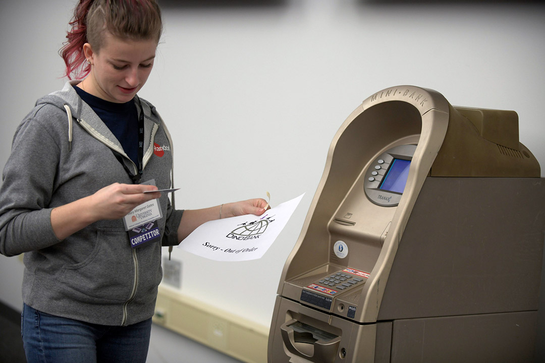 Student stands next to fake ATM.