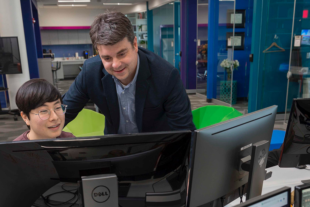 pofessor working with student on computer.