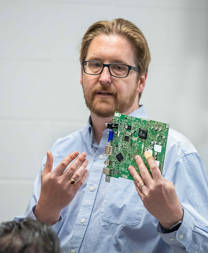 professor holding a circuit board.
