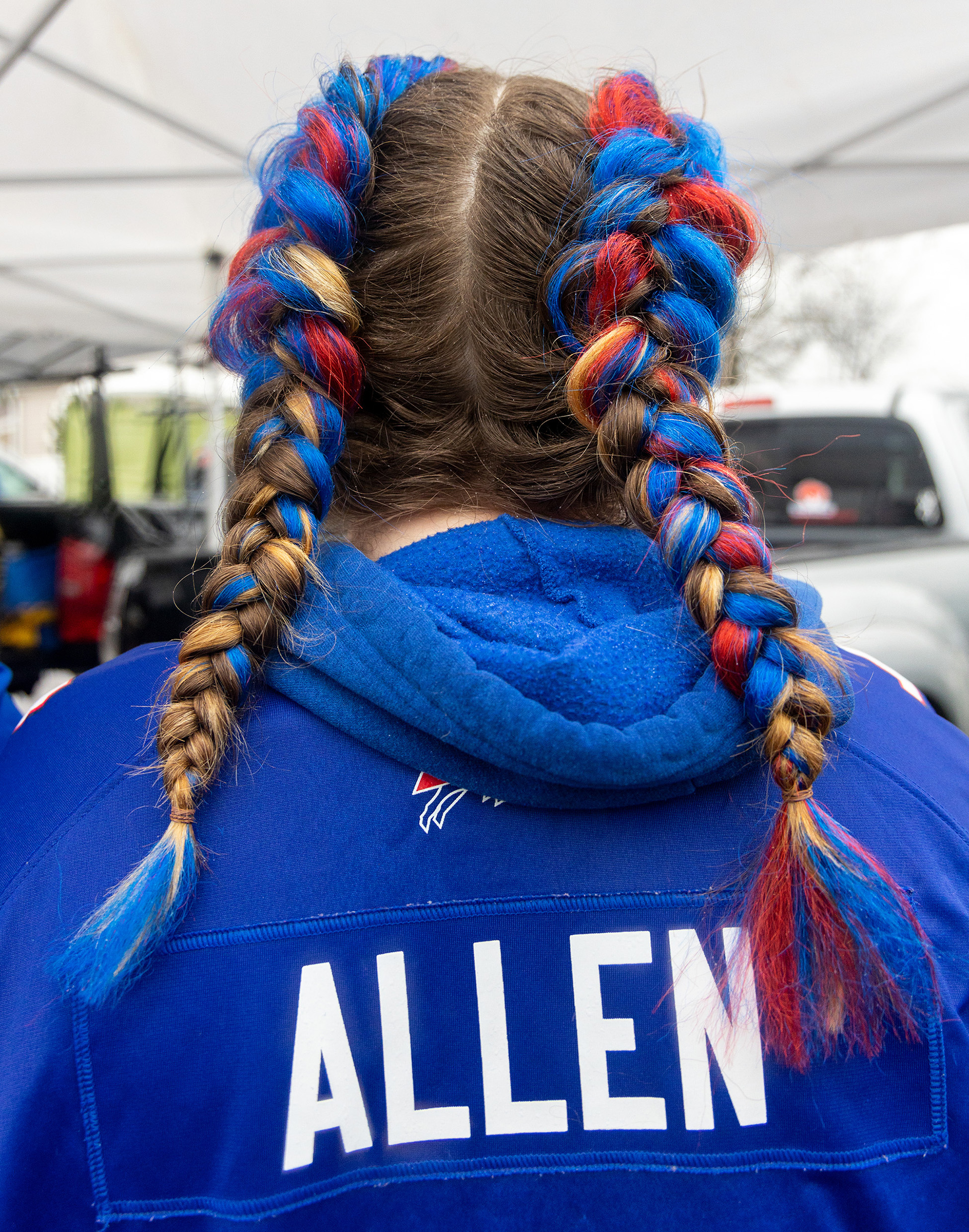 A bills fan wearing a Josh Allen jersey with red and blue pigtails.