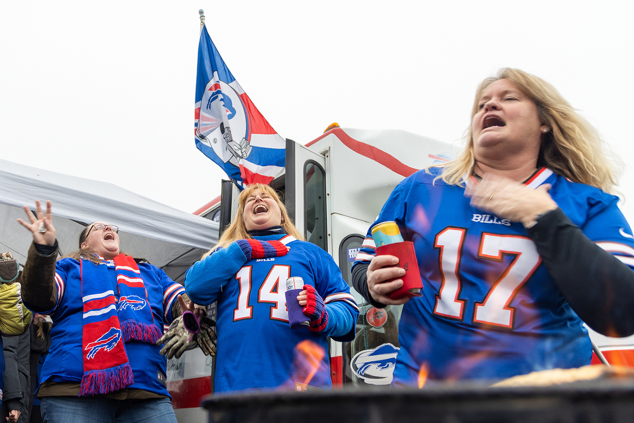 Three women laugh during a tailgate party.