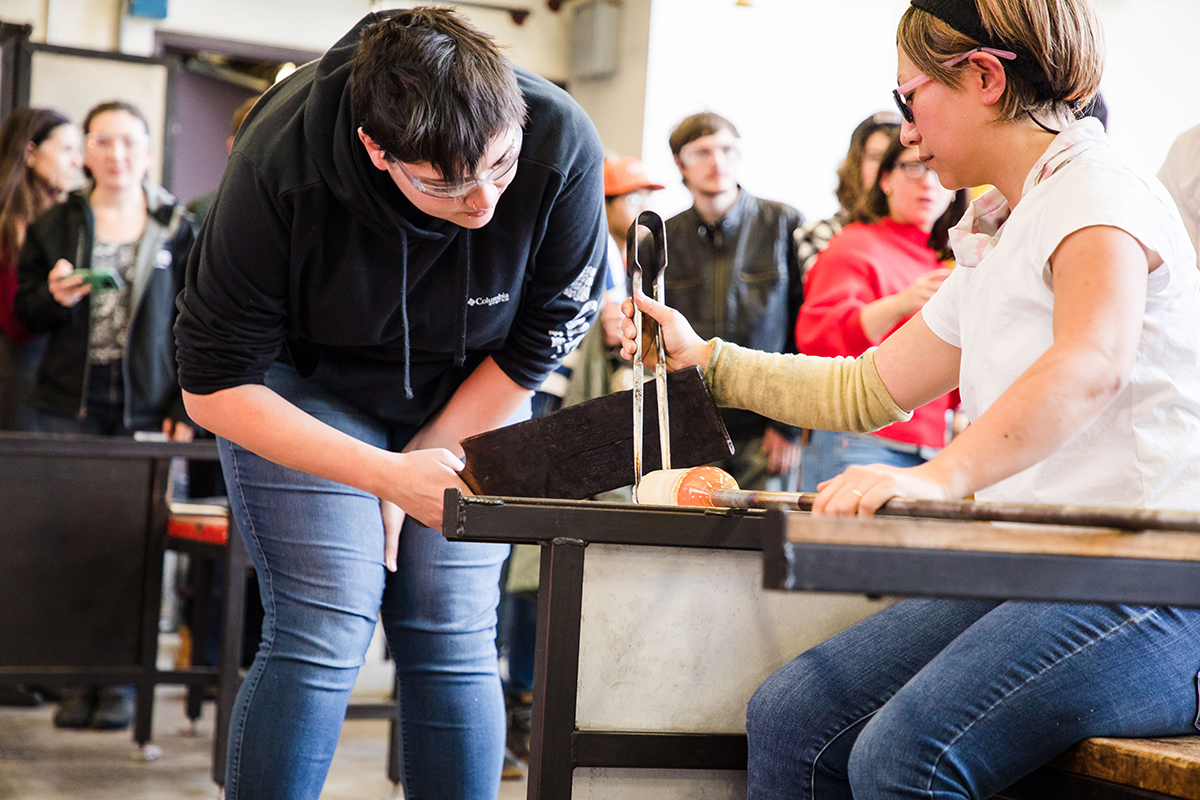 MFA Glass student Kayla Cantu assists Aya Oki with a hot glass demo.