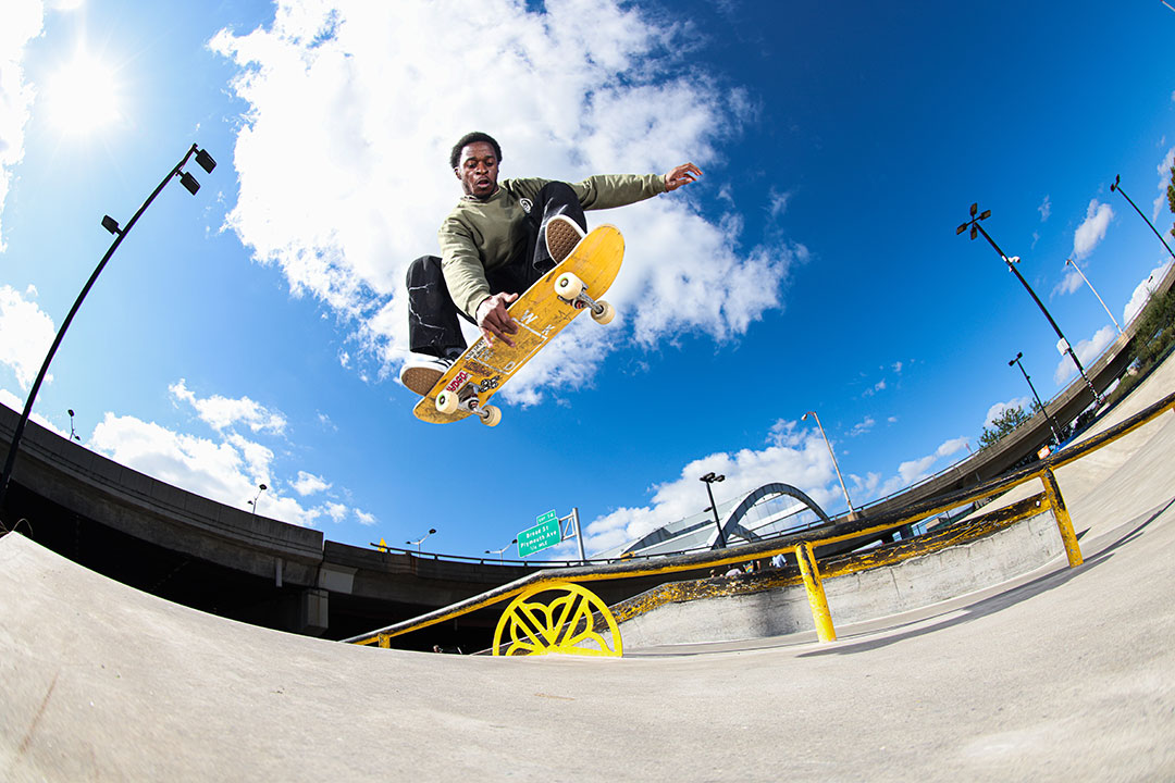 view from the ground of a skateboarder up in the air, grabbing the bottom of the board.