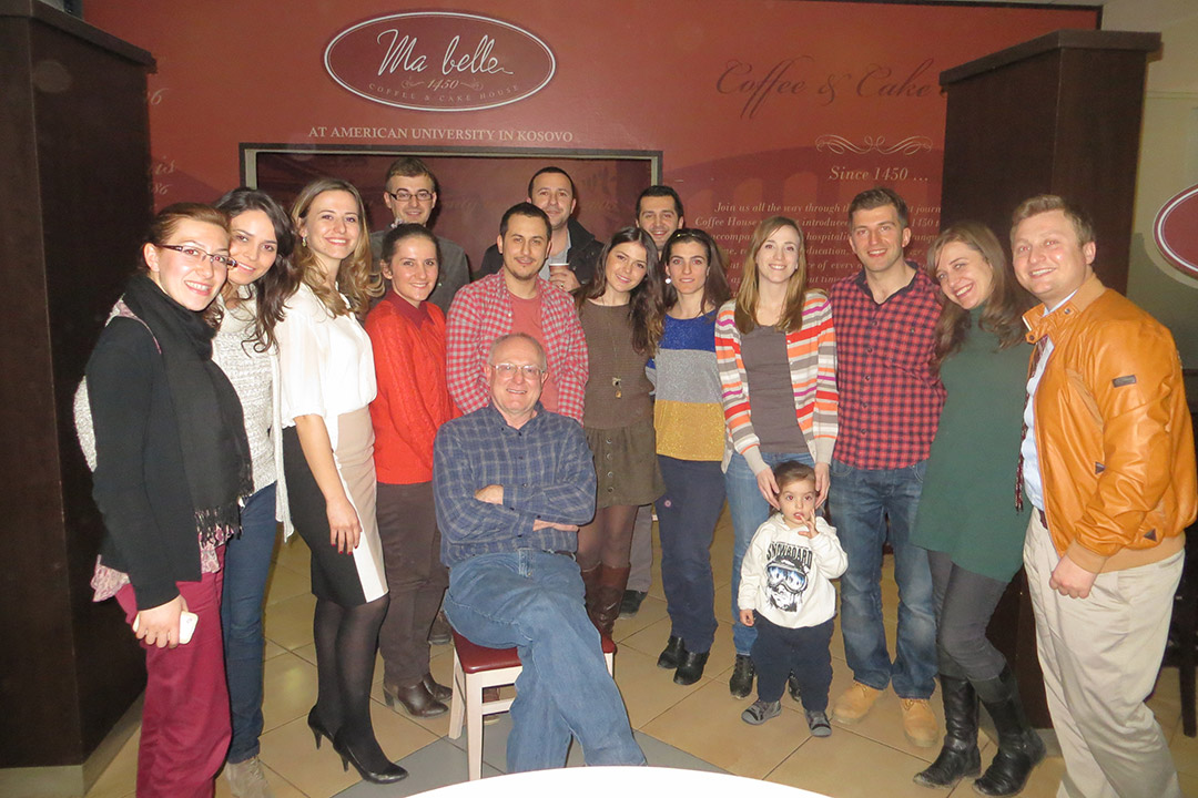 professor posing for photo with students in a restaurant.