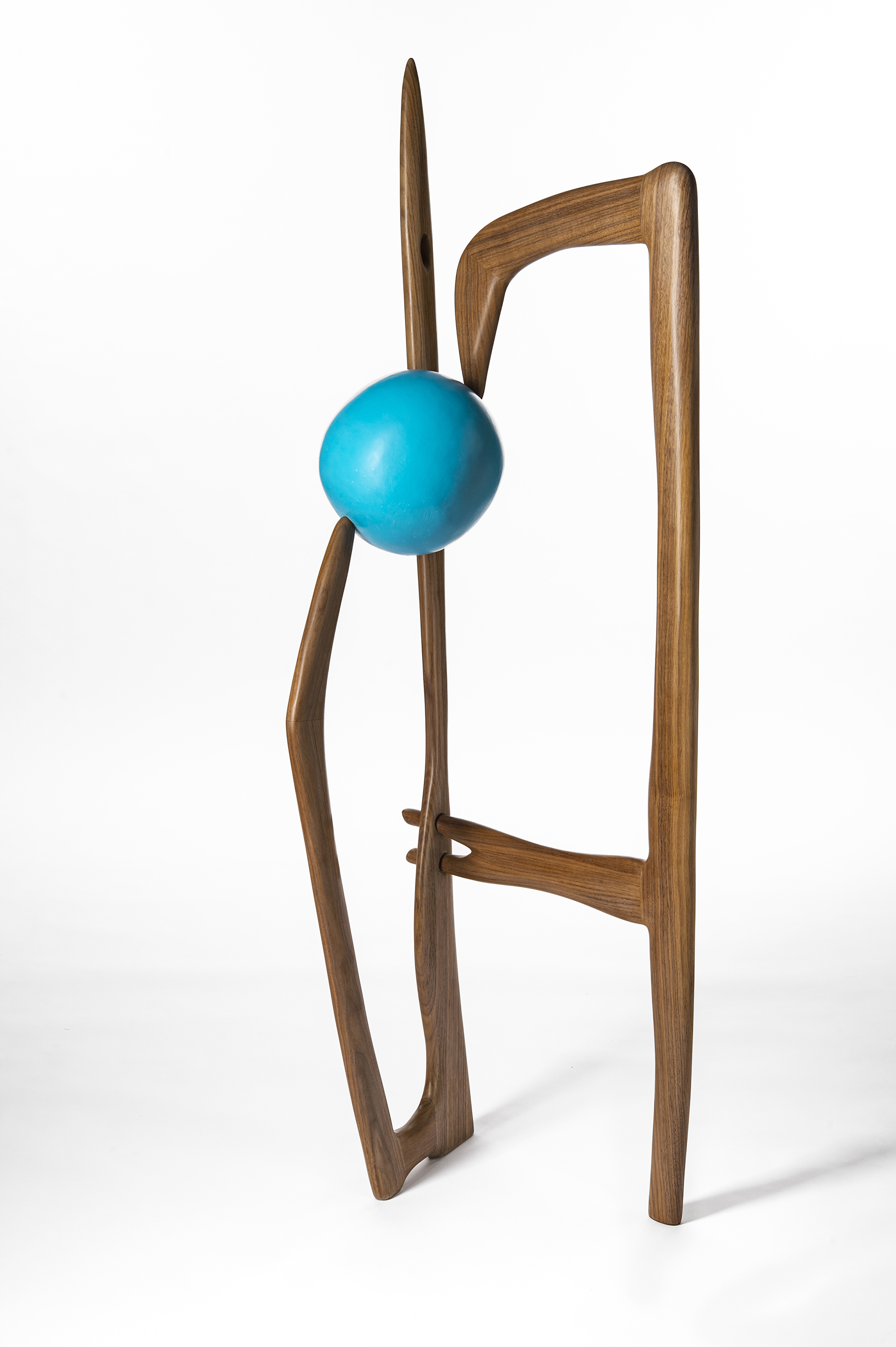 A wood sculpture connected to a large blue ball.