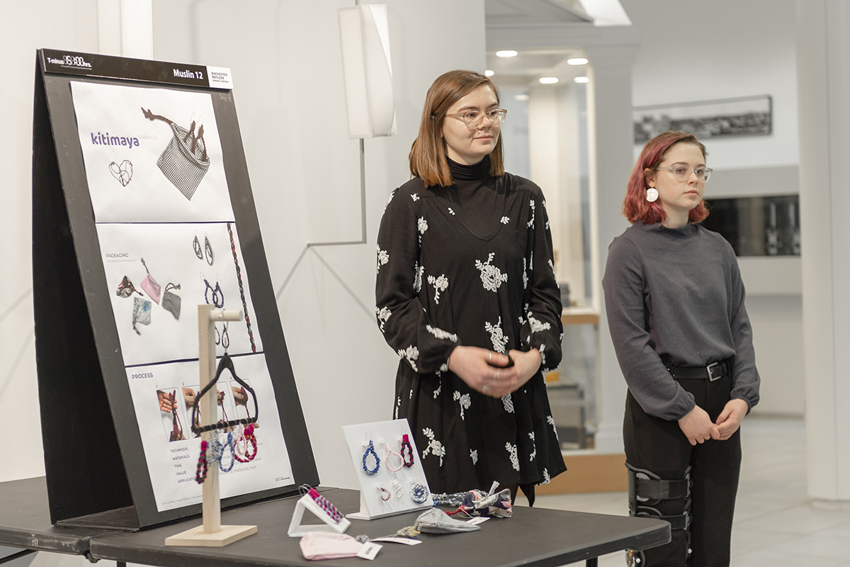 Two students stand beside their winning fabric earring design.
