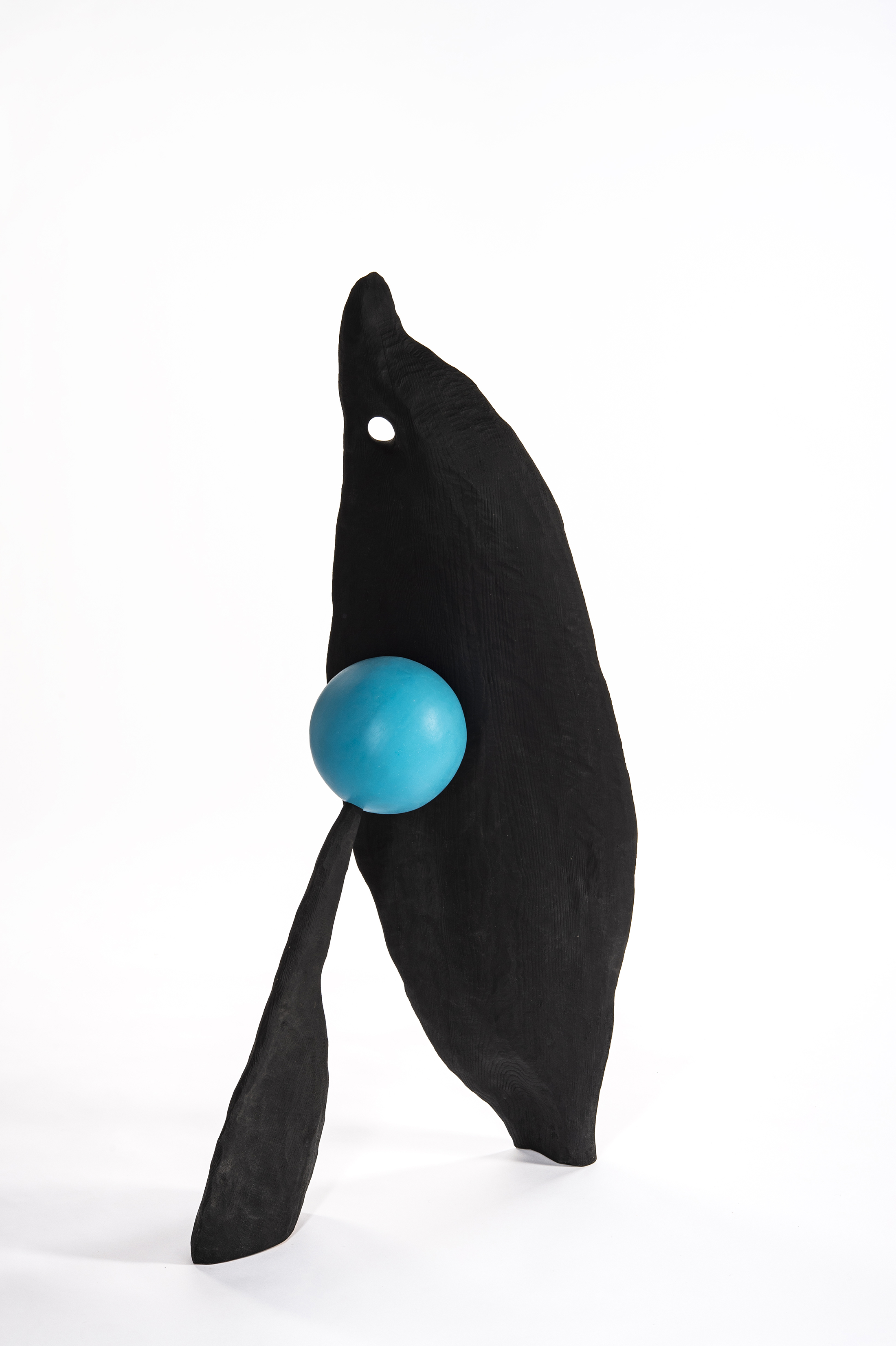 A black sculpture with two large wood pieces sandwiching a blue ball.