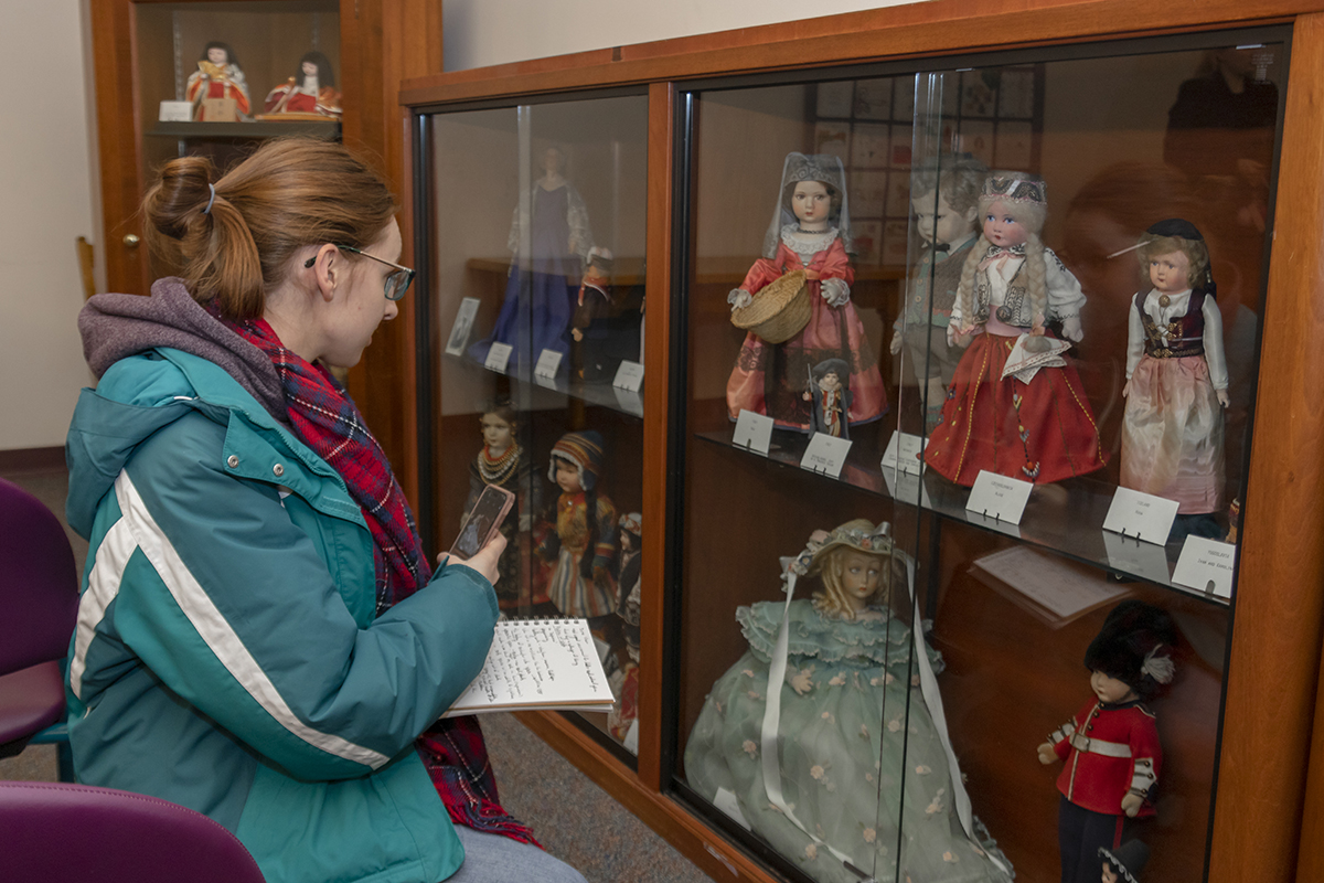 A student observes the doll collection held in the Central Library of Rochester and Monroe County's Secret Room.