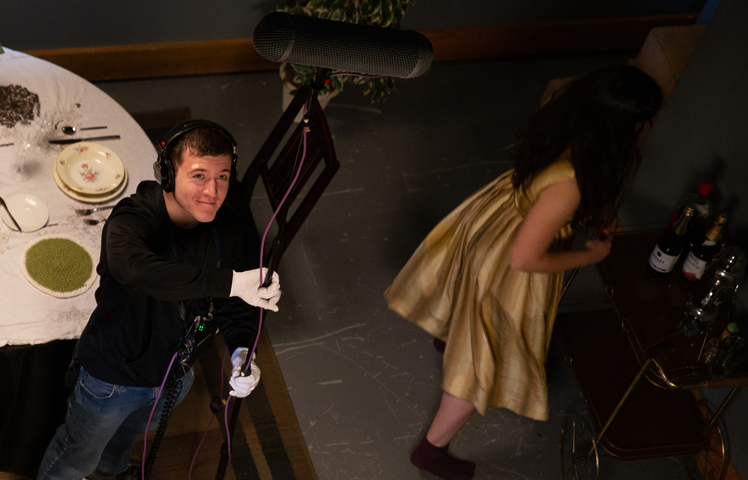 Soundman with white gloves smiling while holding sound equipment.