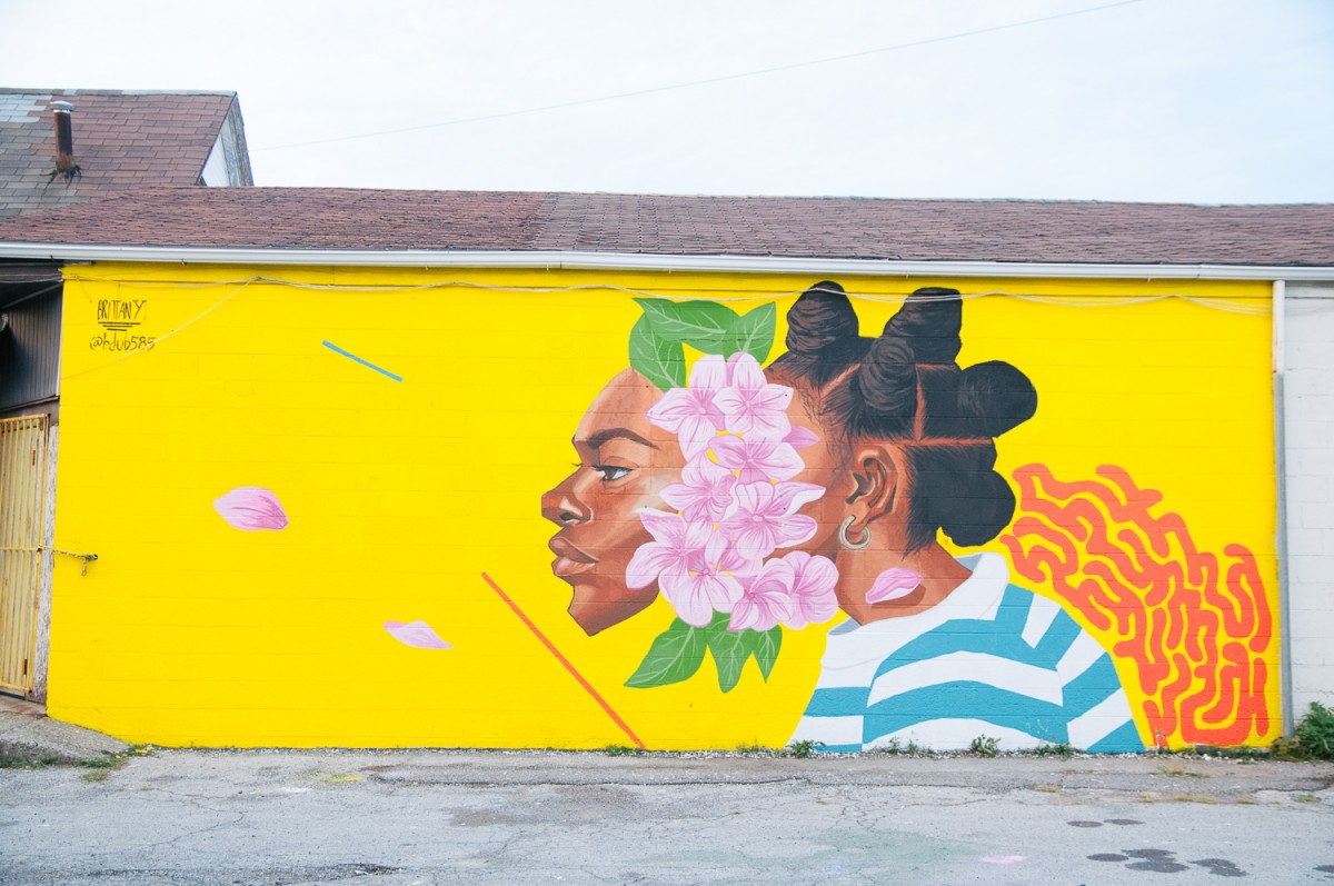 A yellow-background mural featuring a woman with flowers on her face.