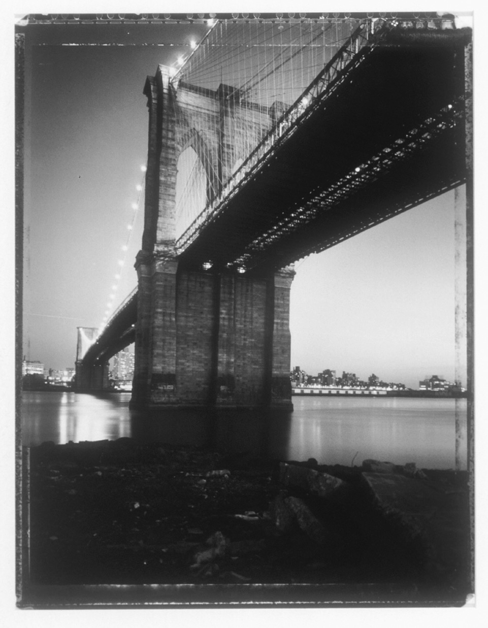 A black and white photo of the Brooklyn Bridge from below.