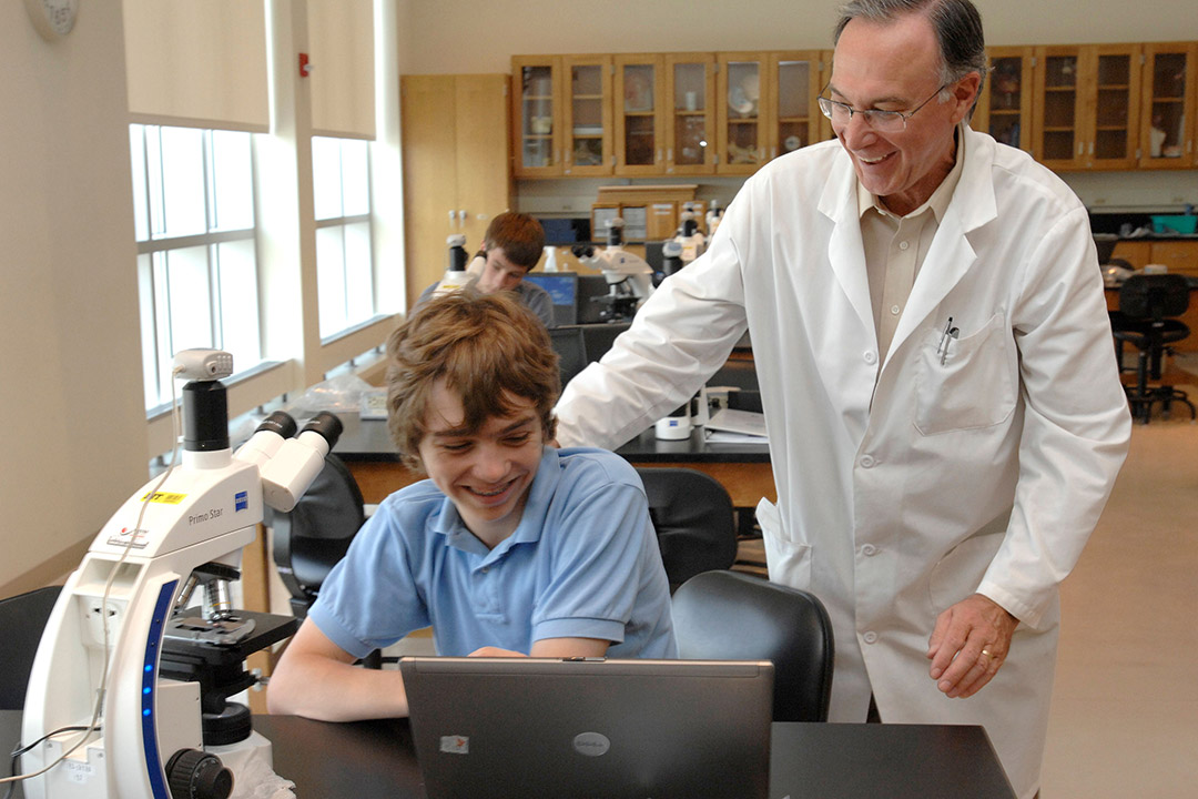 professor working with middle school student in a lab.