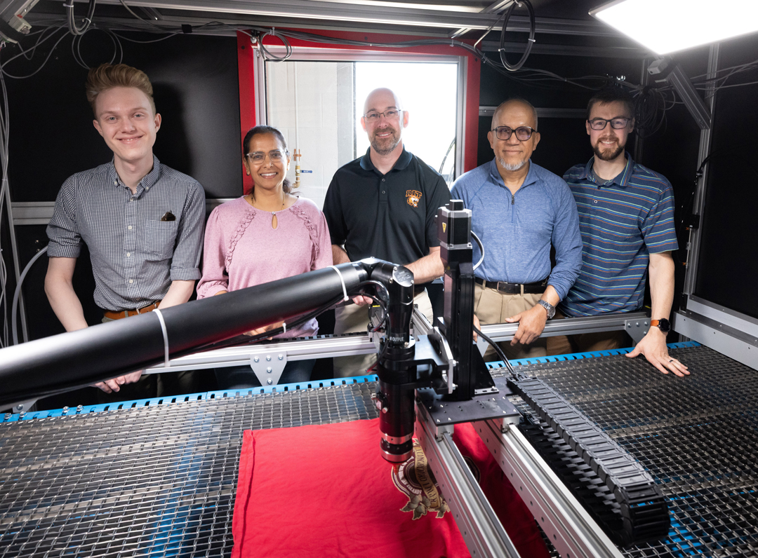 Five people stand behind a worktable