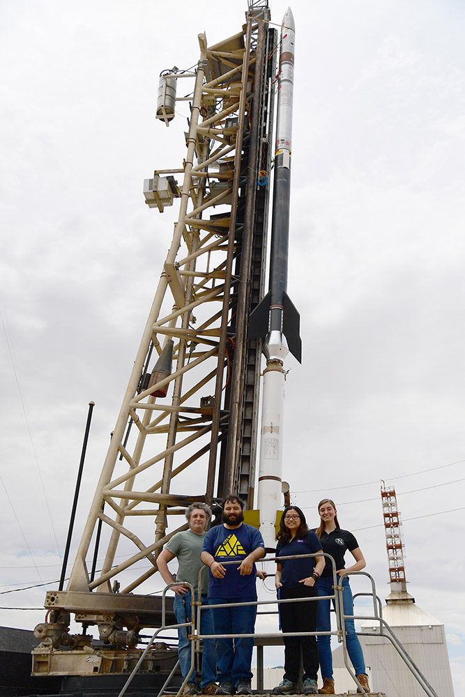 group od four standing near the launchpad of a rocket.