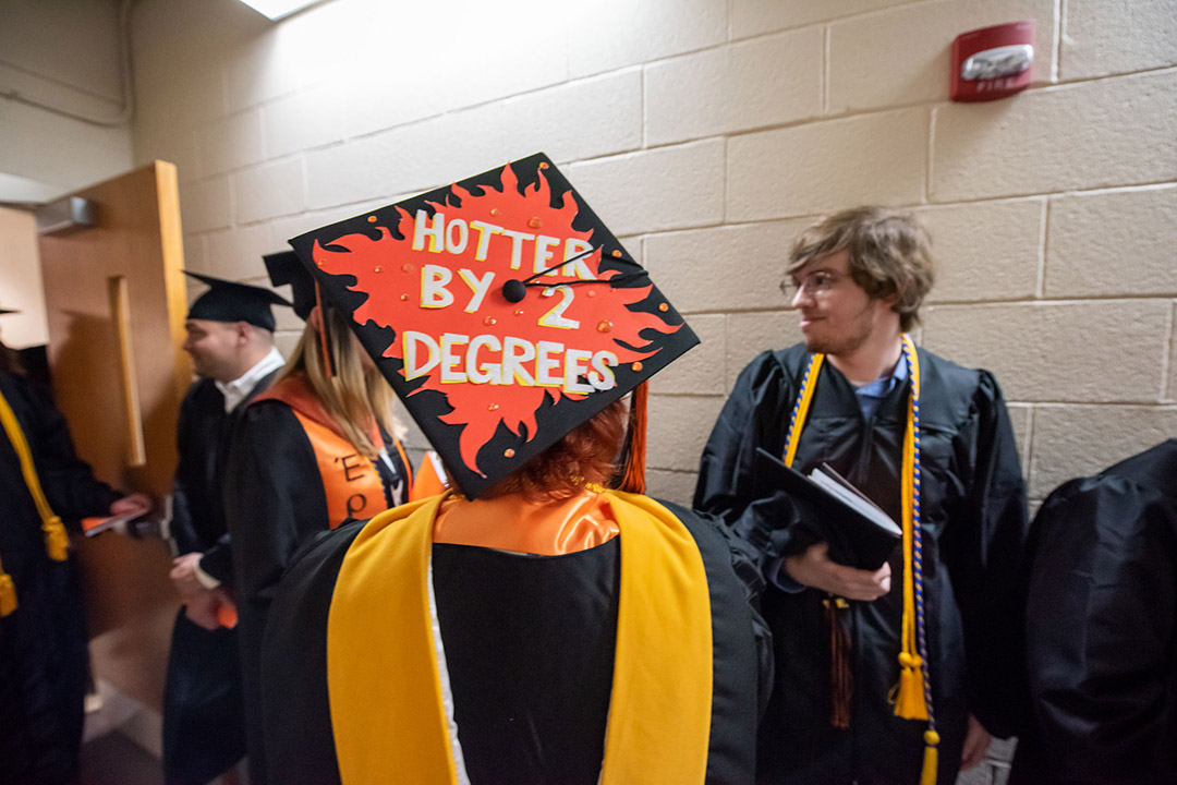 graduating college student with mortarboard that reads, hotter by two degrees.