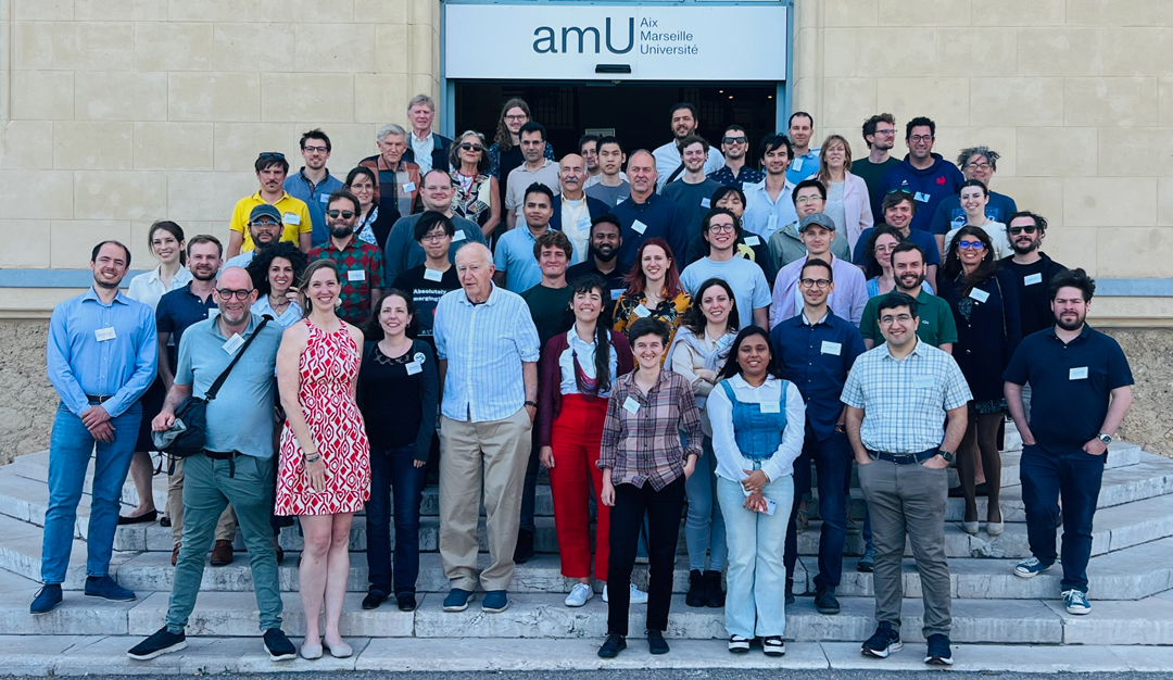 Group of 50 people stand in front of sign that reads amU Aix Marseille Universite.