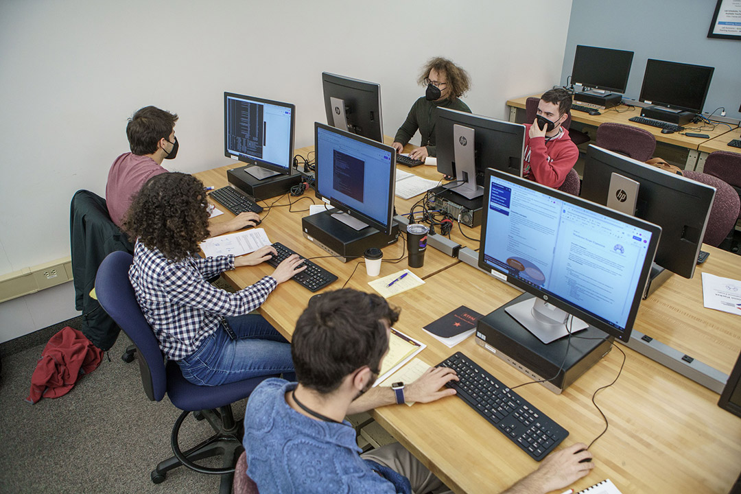 five students sitting at desks with computers.