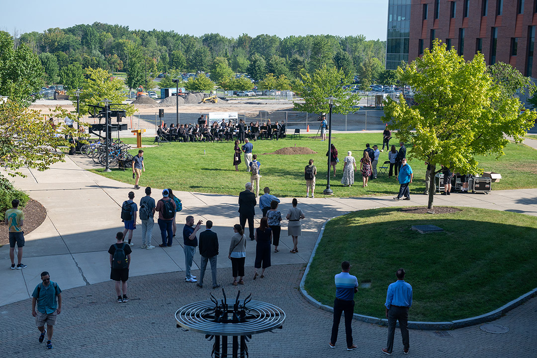 a construction site in the background with a band and ceremonial grounding breaking in the foreground.