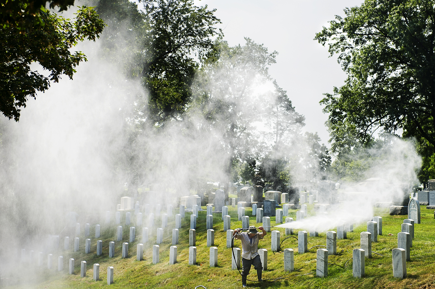 Man in a cemetary sprays large amounts of chemicals