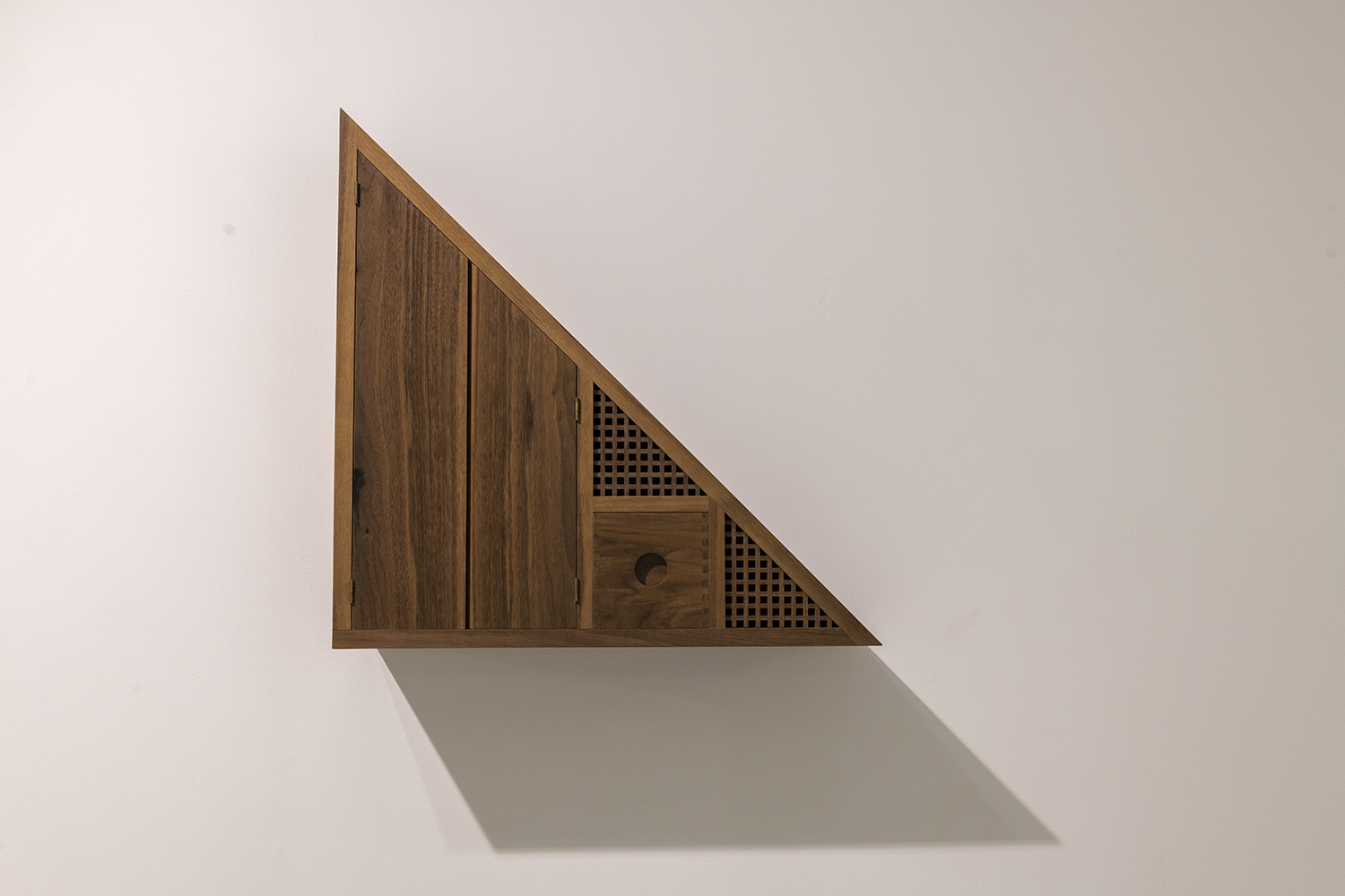 A triangular shaped wooden design mounted on a wall.