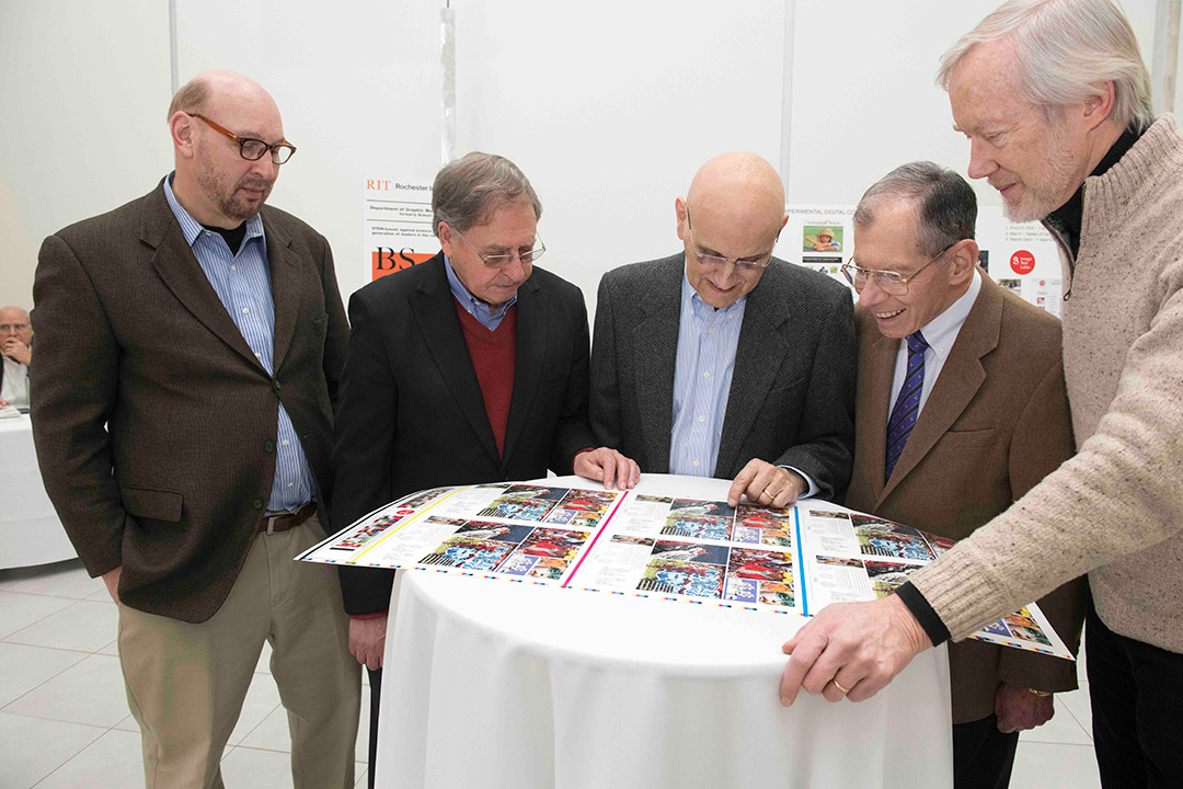 five men standing around a bistro table at a reception.