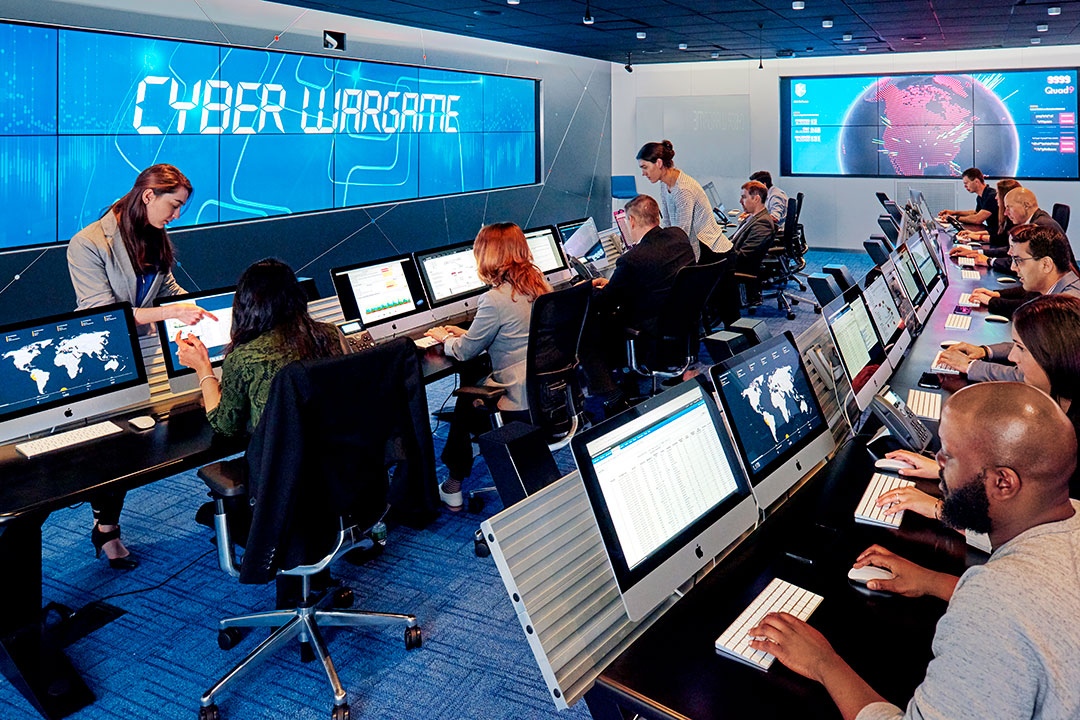 People sit at rows of computers in cyber range.