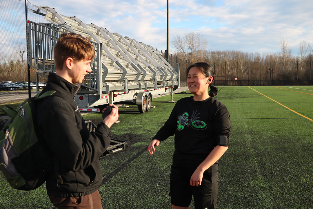 two college students talking on an athletic field.