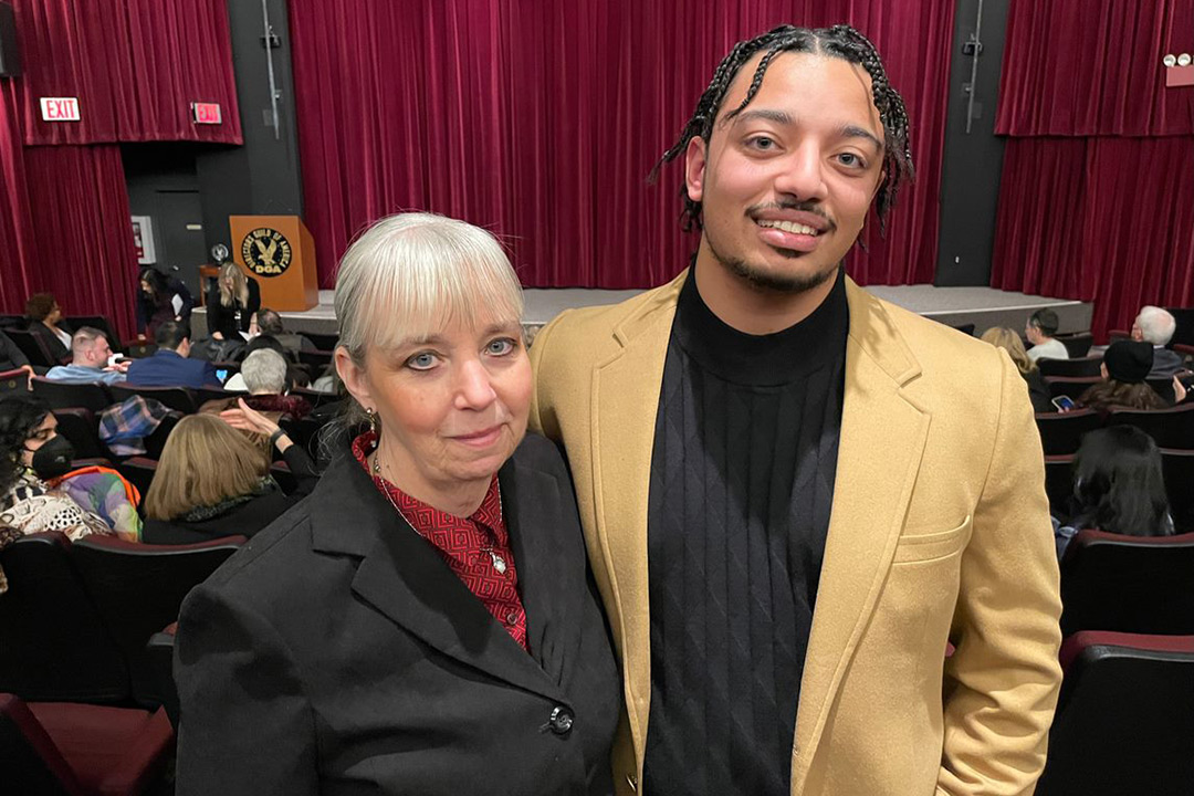 mother and son standing next to each other in a movie theater.