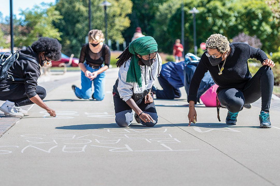 students writing on ground with chalk.