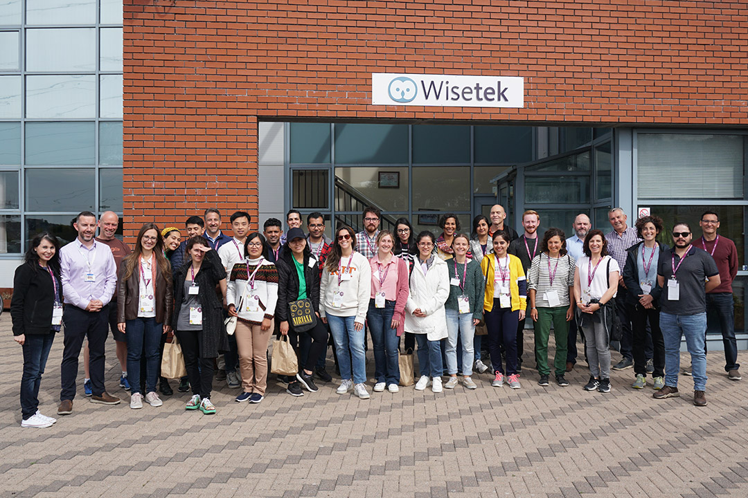 large group of students standing outside a building labeled Wisetek.