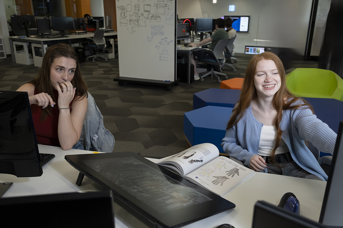 Deanna Moorehead and Maggie Slaughter look at a computer screen together in MAGIC Spell Studios.