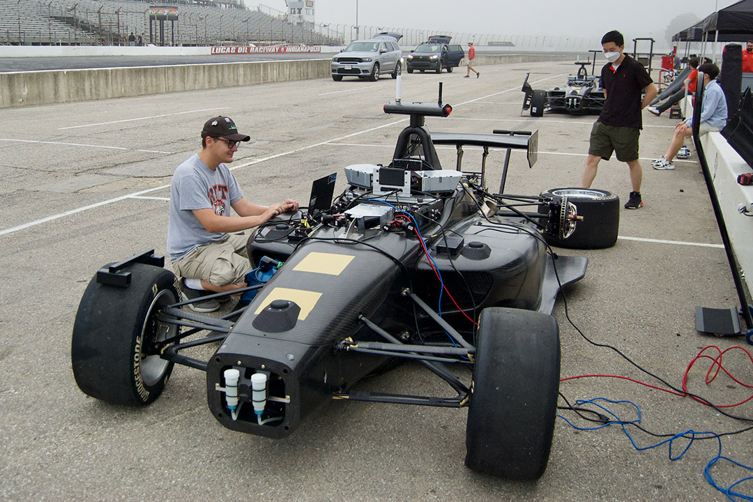 student working on wheel of Indy racecar.