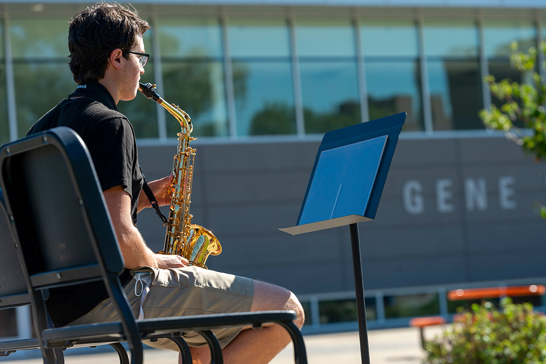 student playing saxophone outside.