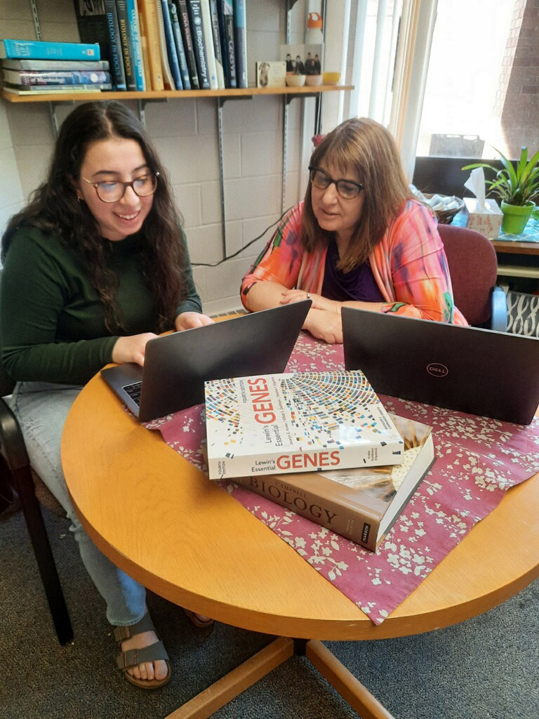 student and professor looking at a computer.