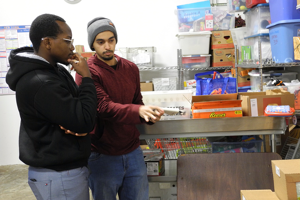 Two graduate students standing at a counter top. One is pointing to a box.