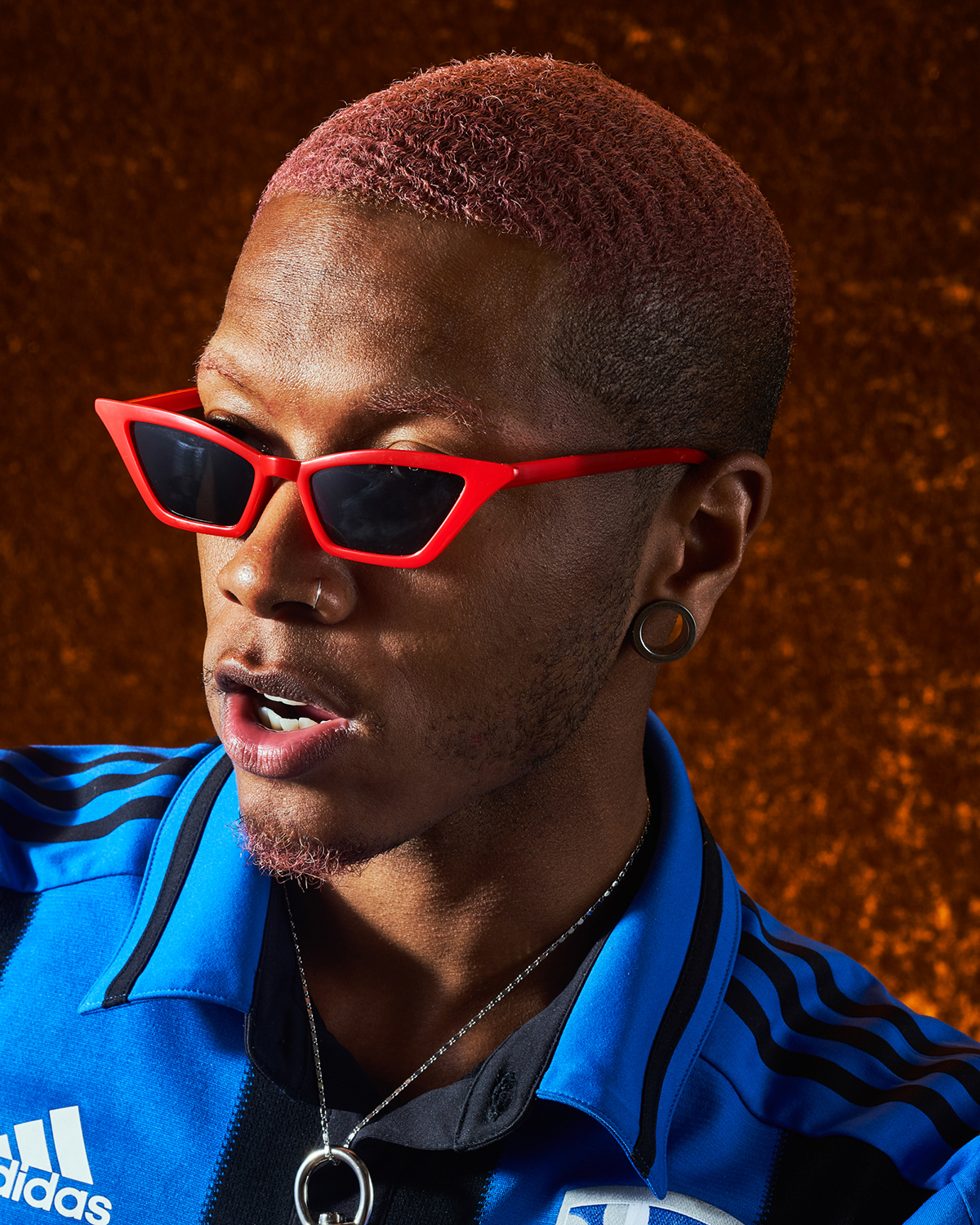 Close-up portrait photography of a man with a nose ring and red sunglasses.