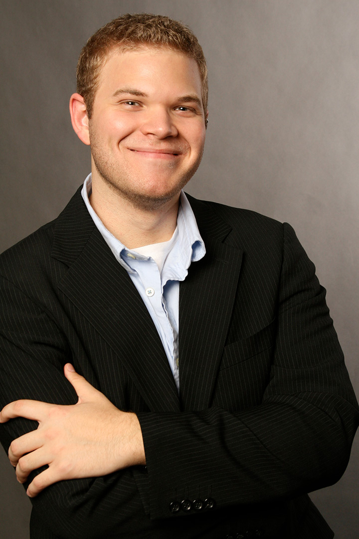 Smiling man wearing black suit jacket and blue shirt