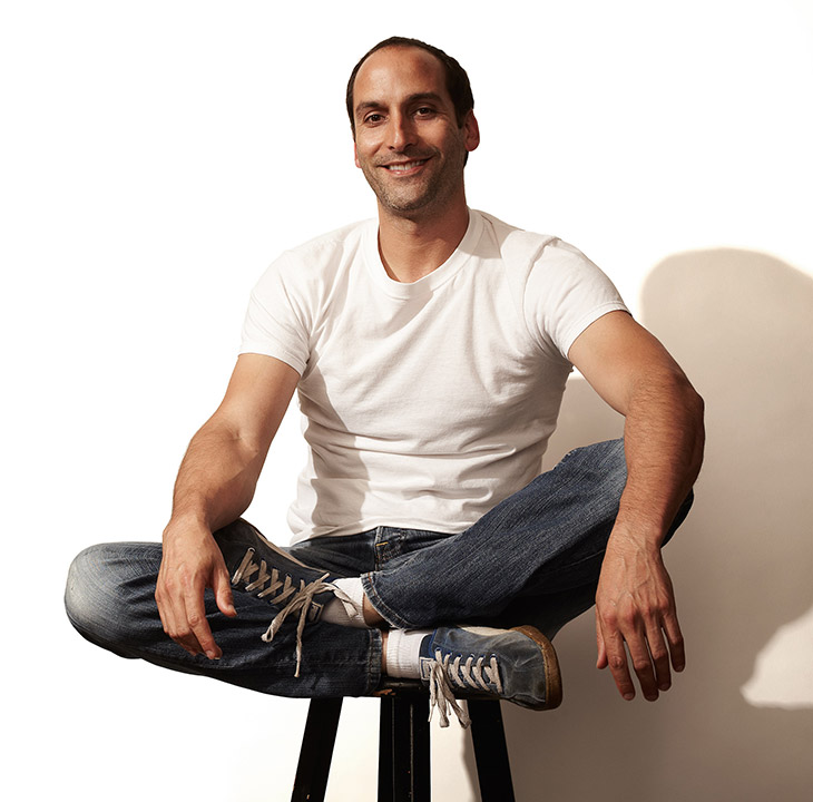 man sitting cross-legged on a stool.